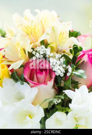Splendida disposizione floreale con rose rosa, gigli gialli e fiori bianchi in un ambiente luminoso Foto Stock