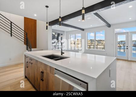 Una cucina con un'isola bianca e elettrodomestici in acciaio inox. La cucina è molto pulita e ben illuminata Foto Stock