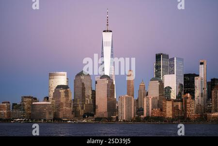 Una splendida vista crepuscolare dello skyline di New York mette in risalto il One World Trade Center, che riflette l'ultima luce del giorno con il lungomare e il bagliore. Foto Stock