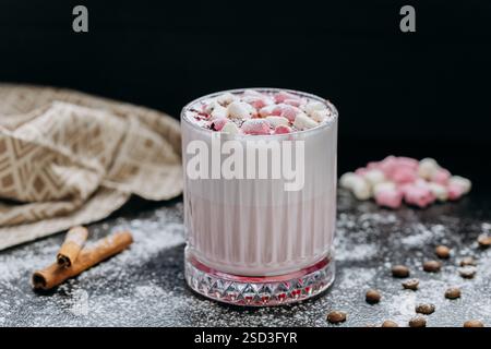 Tazza di cioccolata calda rosa con marshmallow e zucchero a velo su uno sfondo rustico e scuro Foto Stock