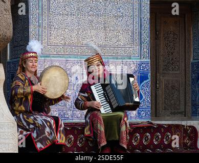 Due musicisti uzbeki suonano la fisarmonica e il tamburo nella moschea estiva all'aperto all'interno della Cittadella Kunya-Ark nella città vecchia di Khiva. Foto Stock