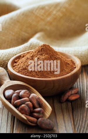 cacao in polvere nel recipiente e fagioli di cacao in paletta sul tavolo Foto Stock
