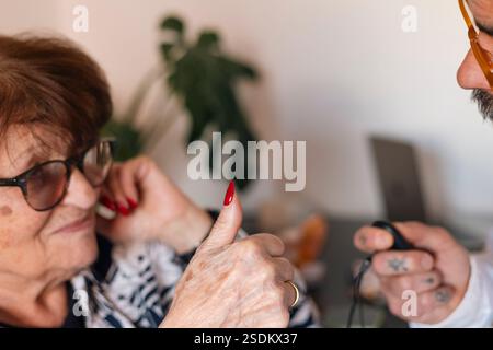 Donna anziana che mostra il pollice in su durante il test dell'udito con audiologo Foto Stock