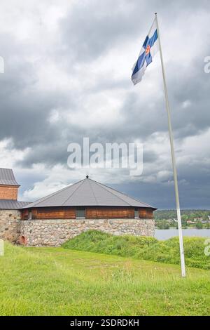 Hämeen Linna, uno storico castello medievale a Hämeenlinna, in Finlandia, con la bandiera finlandese che sventola su un palo. Foto Stock