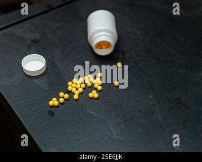 pillole, antibiotici o vitamine versate sulla scrivania, primo piano dello studio Foto Stock
