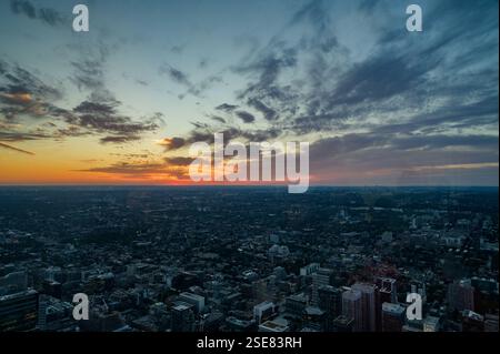 Una vista mozzafiato cattura il tramonto che illumina la città sottostante, con colori vivaci che si riflettono sulle nuvole e sugli edifici. La luce da sera crea Foto Stock