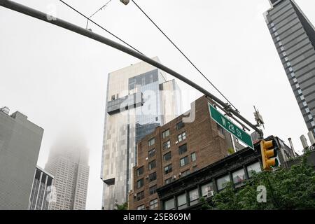 Una giornata nebbiosa a New York rivela un contrasto tra i moderni grattacieli e gli edifici più vecchi lungo la 28th Street, mostrando la vita urbana e l'architettura Foto Stock