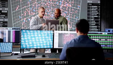 Team informatico diversificato nella sala di controllo che monitora dati e server. Foto Stock