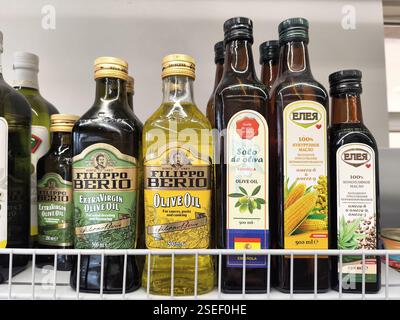 Bottiglie di olio d'oliva di varie marche su uno scaffale in un negozio di alimentari. Foto Stock