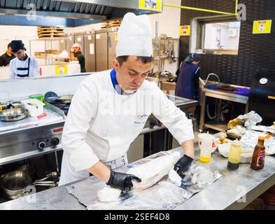 BAKU, AZERBAIGIAN-24 MAY2019 : lo chef prepara anche piatti con gambo di agnello. Il processo di cottura dello chef maschio dello stinco di agnello in una cucina professionale. Cucinare Foto Stock