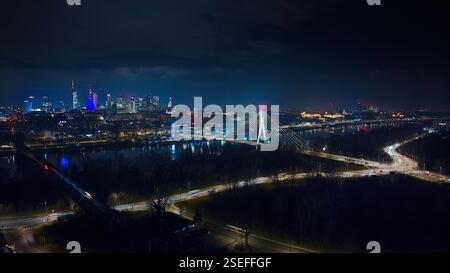 Una spettacolare vista notturna di Varsavia: Ponte Świętokrzyski, scintillanti luci della città e strade piene di movimento dall'alto. Foto Stock