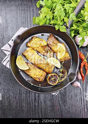 Rosa salmone con il miele, il succo di limone, aglio, peperoncino e la salsa di soia, le fette di limone e un rametto di timo in padella su un tovagliolo, prezzemolo su nero w Foto Stock