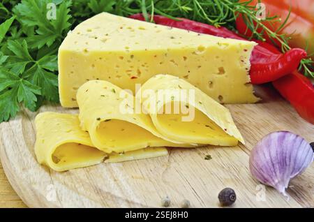 Formaggio con spezie ed erbe aromatiche, prezzemolo, dragoncello, paprika dolce e calda, capsicum, aglio su un tagliere di legno rotondo Foto Stock