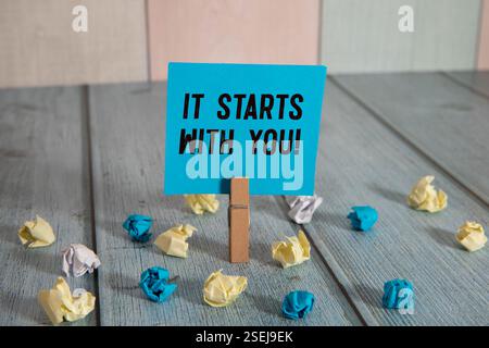 Inizia con le parole scritte su un pezzo di carta bianca strappato con sfondo blu. Concettuale inizia con il simbolo di te. Copia spazio. Foto Stock