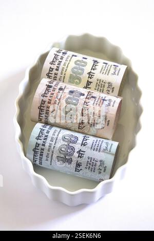 Concetto, valuta indiana centocinquecento e mille rupie in ciotola Foto Stock