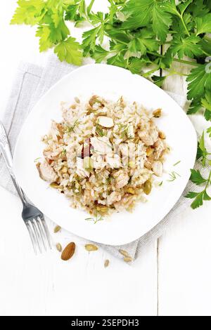 Insalata di salmone affumicato, riso, semi di girasole e di zucca, mandorle, condite con miele e olio d'oliva in un piatto su un asciugamano, prezzemolo e forchetta sul dorso Foto Stock