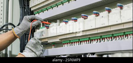 Un ingegnere elettrico verifica regolarmente il funzionamento dell'armadio elettrico per la manutenzione. Foto Stock