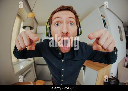 Ritratto di un bellissimo giovane con le cuffie Ascolta la musica divertiti e punta verso di te Foto Stock