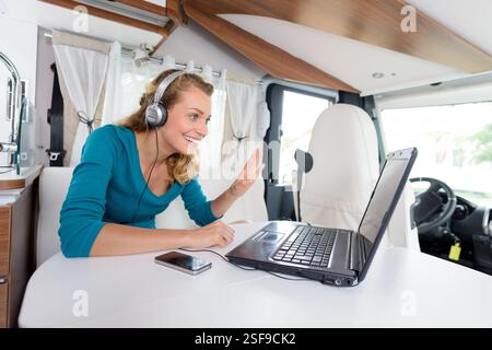 donna che usa skype in un'auto da campeggio Foto Stock