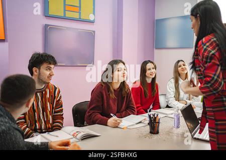 Insegnante donna che spiega il soggetto ai suoi studenti adolescenti alla scuola di lingue Foto Stock