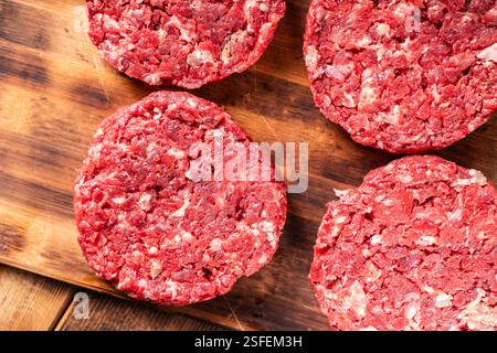 Hamburger di manzo crudo fatto in casa su un asse di legno. Preparazione dell'hamburger. Vista dall'alto. Foto di alta qualità. Foto Stock