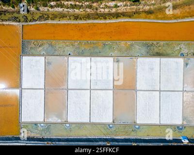 Vista aerea delle grandi saline rettangolari utilizzate per la produzione del sale, con un gradiente di colori che vanno dal sale bianco cristallizzato all'arancio e. Foto Stock