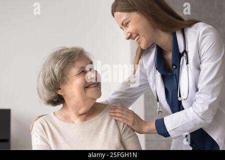 Una donna che ride medico abbraccia le spalle di una paziente anziana grata Foto Stock