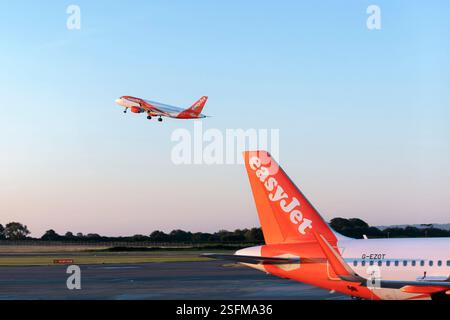 Aeroporto di Bristol Regno Unito. Un aereo easyjet che decolla la mattina presto. Gli aerei easyJet vengono visualizzati parcheggiati sulla pista Foto Stock