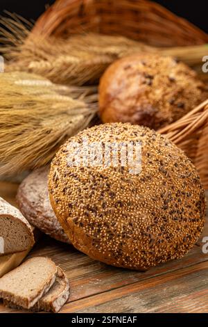 Pane appena sfornato esposto su un rustico tavolo in legno con gambi di grano Foto Stock