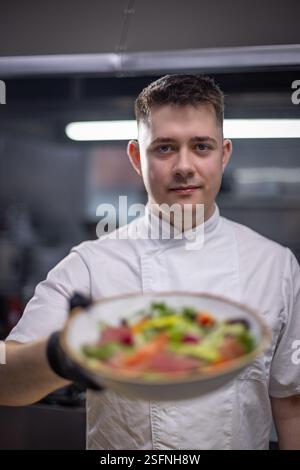 Lo chef tiene un'insalata gourmet nella cucina del ristorante Foto Stock