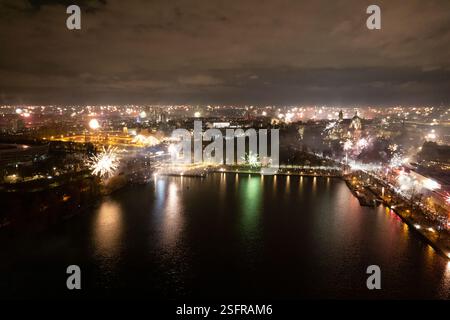 La vista mozzafiato mette in mostra una città illuminata da fuochi d'artificio, che si riflette splendidamente sull'acqua di notte, l'Hannover Maschsee Drone Capodanno 2025 FPV Foto Stock