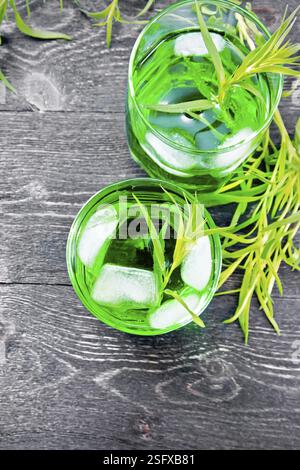 Limonata di dragoncello con ghiaccio in due bicchieri, rametti di estragone su uno sfondo di legno da sopra Foto Stock