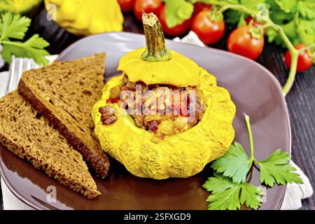 Squash giallo con ripieno di carne, pomodori e peperoni, pane nella piastra, i pomodori, il prezzemolo su tavole di legno sfondo Foto Stock