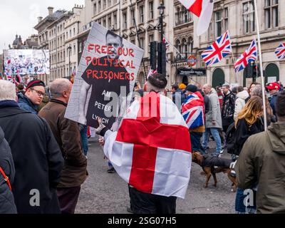 Il manifestante con la bandiera inglese sul retro regge il cartello "Free Tommy Robinson" a Whitehall, Londra. Evento "Stop the Isolation" o "Unite il Regno". Foto Stock