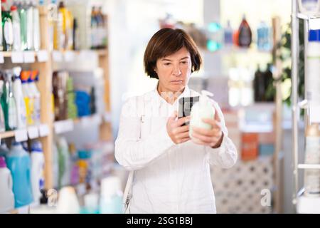 Donna anziana che esegue la scansione del codice qr per il sapone liquido Foto Stock