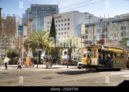 I pedoni attraversano Powell St a Union Square, San Francisco. Sono visibili un albero di Natale di Macy e una funivia. Foto Stock