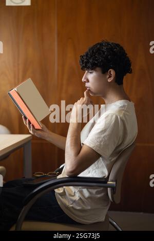 Una persona che legge e analizza un libro, focalizzata sulla comprensione del suo contenuto. Ideale per temi di studio, crescita intellettuale e analisi letteraria. Foto Stock