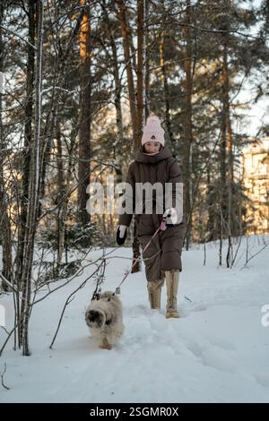 Donna che cammina attraverso la foresta innevata con un cane a Oslo Foto Stock