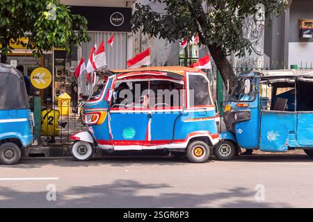 Giacarta, Indonesia - 10 agosto 2024: Un bajaj decorato con la bandiera indonesiana è parcheggiato sul lato della strada a Giacarta. Un pubblico a tre ruote Foto Stock