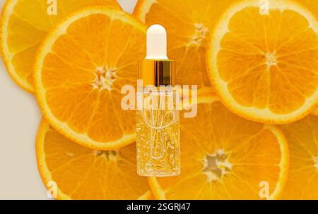 Siero con vitamina C in flacone trasparente. Sfondo di arance. Concetto di bellezza e salute. Mockup per il tuo progetto con spazio di copia Foto Stock