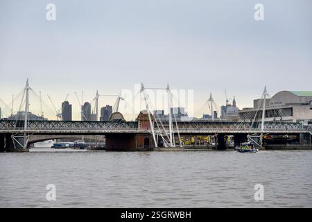 Londra, Regno Unito. Hungerford Rail Bridge e Golden Jubilee Bridges (pedoni) sul fiume Tamigi. Royal Festival Hall sulla South Bank (a destra) Foto Stock