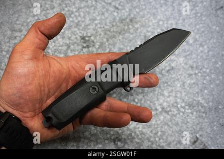 Coltello compatto tattico con lama fissa in mano a un uomo. Foto Stock