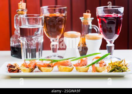 Tapas e bevande assortite servite su un piatto bianco in un accogliente ambiente ristorante Foto Stock