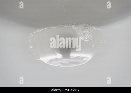Lavabo bianco in ceramica per il bagno con acqua che scende attraverso lo scarico. Con spazio per copiare. Foto di alta qualità Foto Stock
