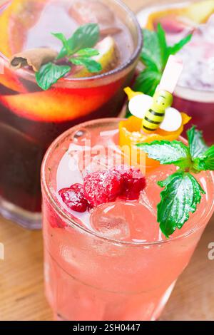 Rinfrescanti cocktail estivi serviti con frutta ed erbe aromatiche ad un raduno all'aperto in un'atmosfera vivace Foto Stock