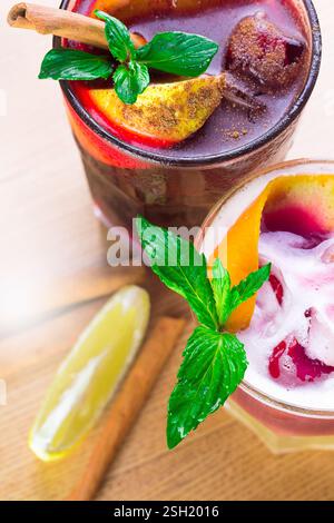 Cocktail rinfrescanti adornati con frutta fresca e menta serviti in un bar all'aperto soleggiato durante l'estate Foto Stock