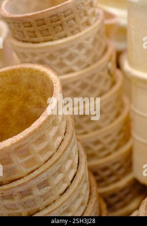 Ci sono molti coni per gelato vuoti impilati, primi piani, cibo astratto Foto Stock