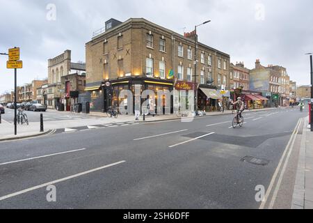 Ciclista su Stoke Newington Church Street, Londra, vicino a un cartello di chiusura della strada. Pedoni e negozi sono visibili. Foto Stock