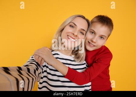 Madre e figlio felici che fanno selfie su sfondo arancione Foto Stock