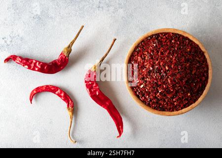 Peperoncino rosso. Peperoncino rosso in una ciotola di legno su una superficie grigia. Fiocchi di peperoncino secchi Foto Stock